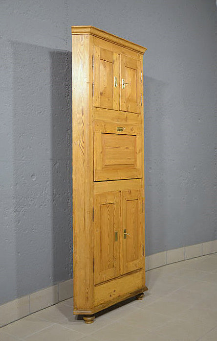 Linke Seitenansicht des restaurierten antiken Biedermeier Eckschranks aus Kiefer mit honigfarbener Oberflaeche. Lieferung persoenlich deutschlandweit. Besichtigung im Moebellager Bargfeld Stegen.