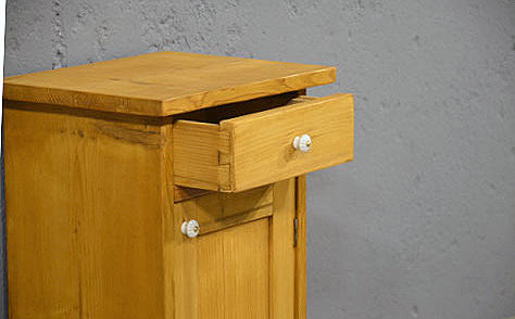 Geöffnete Schublade mit Porzellanknopf des Jugendstil Nachtschranks, restauriert und funktional. Wir liefern zuverlässig, kostengünstig und persönlich – deutschlandweit bis in Ihr Zuhause. Nach Terminvereinbarung können Sie dieses Möbelstück in unserem Möbellager in Bargfeld-Stegen besichtigen.