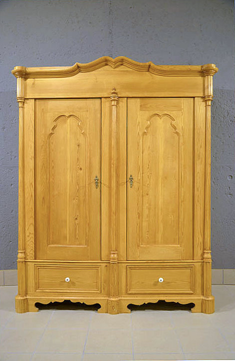 Antiker Louis Philippe Kleiderschrank um 1850 aus D&auml;nemark, massiv aus Kiefernholz gefertigt, fachm&auml;nnisch restauriert und zerlegbar. Im Frontbereich zwei formsch&ouml;ne S&auml;ulen mit feinen Linienverzierungen. Der Deckel zeigt eine elegant gewellte Form mit passender Ornamentik. Zwei gro&szlig;e Schubladen mit Keramikgriffen. Pers&ouml;nliche Lieferung deutschlandweit, Besichtigung im M&ouml;bellager nach Terminvereinbarung.
