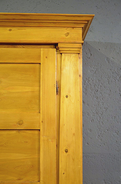 Detail des Oberteils mit schlicht profiliertem Kranz, unterstreicht die klare Formensprache und den eleganten Charakter dieses breiten Biedermeier Schranks. 