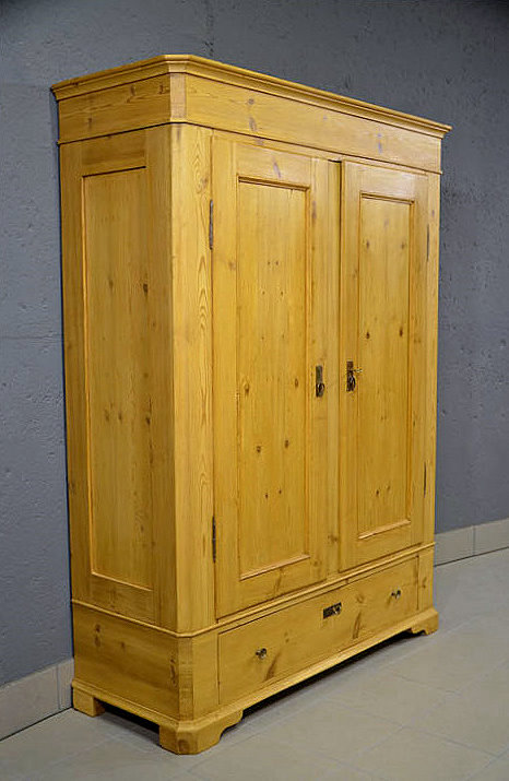 Linke Seitenansicht des antiken Biedermeier Dielenschranks aus massiver Kiefer, im hell warmen Honigton. Schlichte Linienführung, harmonische Proportionen, wohnfertig restauriert. 