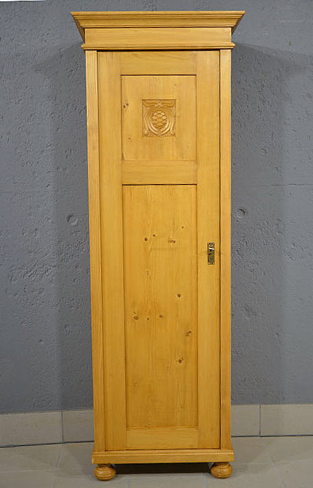 Antiker 1-türiger Kleiderschrank aus dem Jugendstil um 1900, massives Kiefernholz, restauriert und honigfarben gewachst, mit floralem Ornament im oberen Türbereich. Nach Terminvereinbarung können Sie dieses Möbelstück gerne in unserem Möbellager in Bargfeld-Stegen besichtigen. Wir liefern zuverlässig, kostengünstig und persönlich – deutschlandweit bis in Ihr Zuhause.