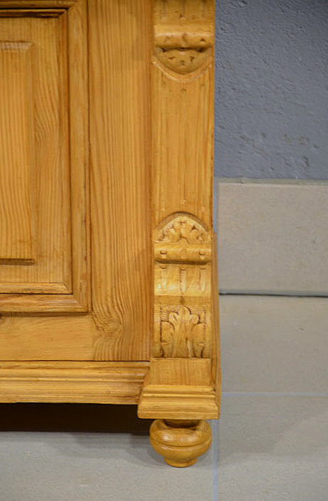 Detailansicht des Sockelbereichs des antiken Halbschranks aus massivem Kiefernholz. Wir liefern zuverl&auml;ssig, kosteng&uuml;nstig und pers&ouml;nlich &ndash; deutschlandweit bis in Ihr Zuhause. Nach Terminvereinbarung k&ouml;nnen Sie dieses M&ouml;belst&uuml;ck gerne in unserem M&ouml;bellager in Bargfeld-Stegen besichtigen.