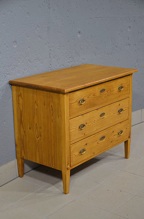 Linke Seitenansicht der schlichten Biedermeier Kommode aus massiver Kiefer mit konisch zulaufenden Spitzbeinen