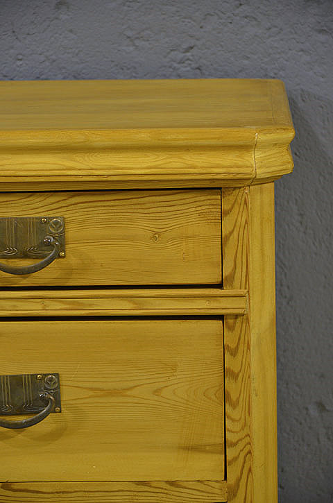 Linke Seitenansicht der antiken Kommode aus massiver Kiefer mit schlichter Gestaltung und ruhiger Linienfuehrung. Wir liefern zuverl&auml;ssig, kosteng&uuml;nstig und pers&ouml;nlich &ndash; deutschlandweit bis in Ihr Zuhause. Nach Terminvereinbarung k&ouml;nnen Sie dieses Moebelstueck gerne in unserem Moebellager in Bargfeld-Stegen besichtigen. 