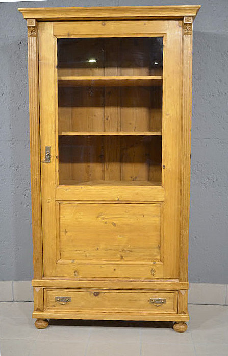 Antike 1 tuerige gruenderzeit vitrine aus massivem Kiefernholz in warmem Honigton in der Frontansicht restauriert und wohnfertig vorbereitet. Wir liefern zuverlässig, kostengünstig und persönlich – deutschlandweit bis in Ihr Zuhause. Nach Terminvereinbarung können Sie dieses Möbelstück gerne in unserem Möbellager in Bargfeld-Stegen besichtigen.